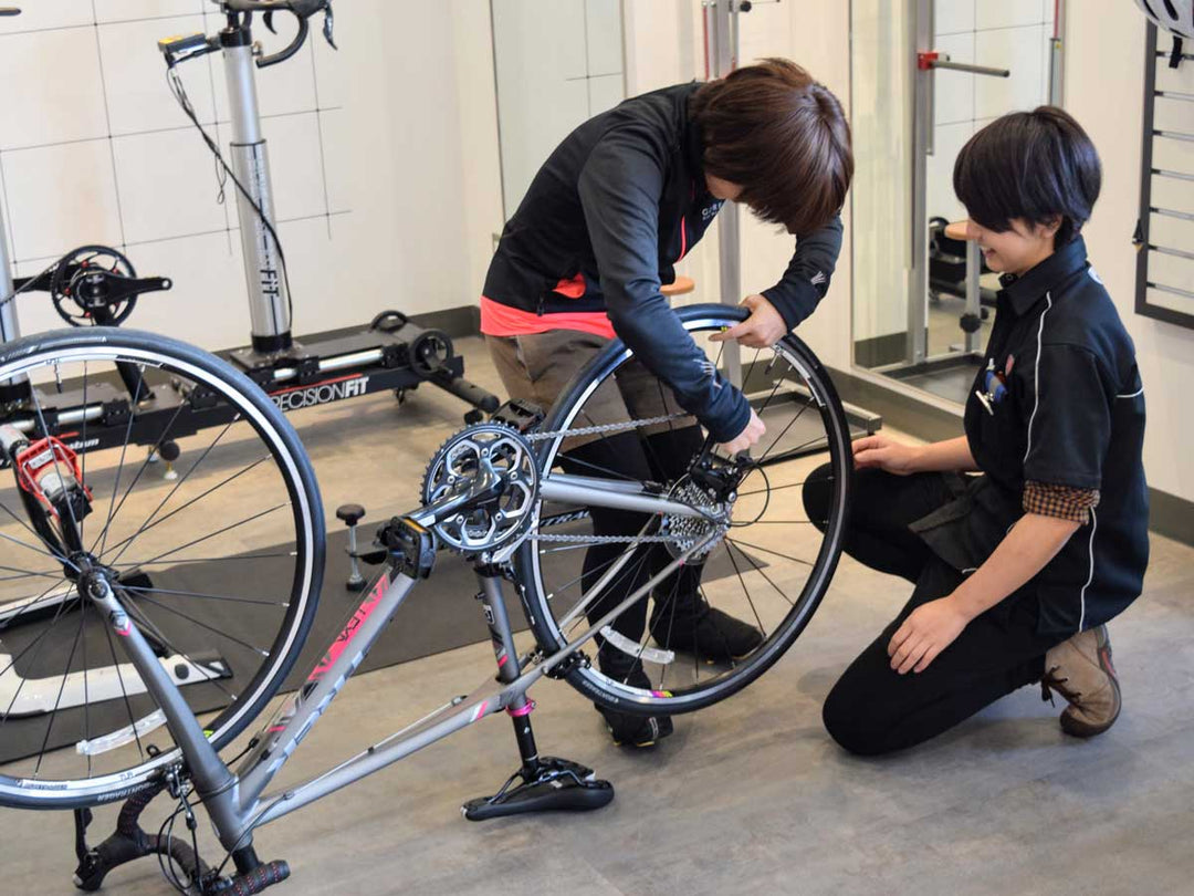 車体をひっくり返して後輪の外し方をレクチャーしている様子