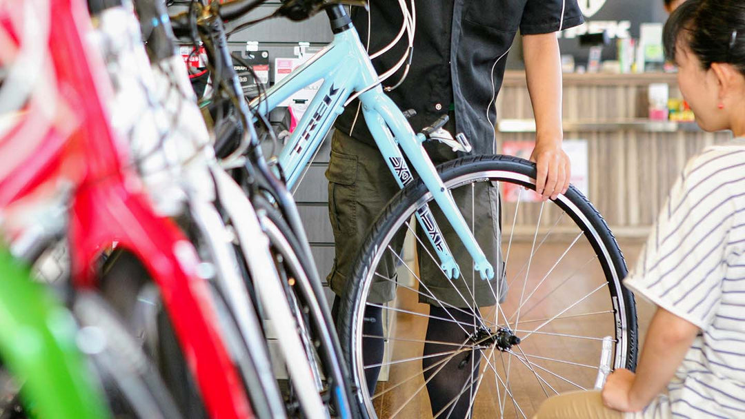 クロスバイクの前輪の外し方をお客様の前で実演しているスタッフの様子