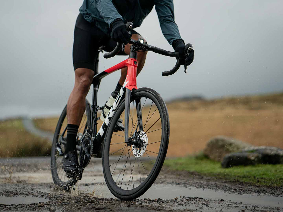 水溜まりのある砂利道を走るロードバイクの写真