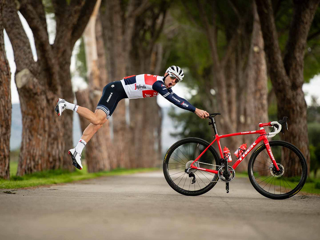 ロードバイクの後方からサドルに手を当ててジャンプして人が浮いているように見える写真