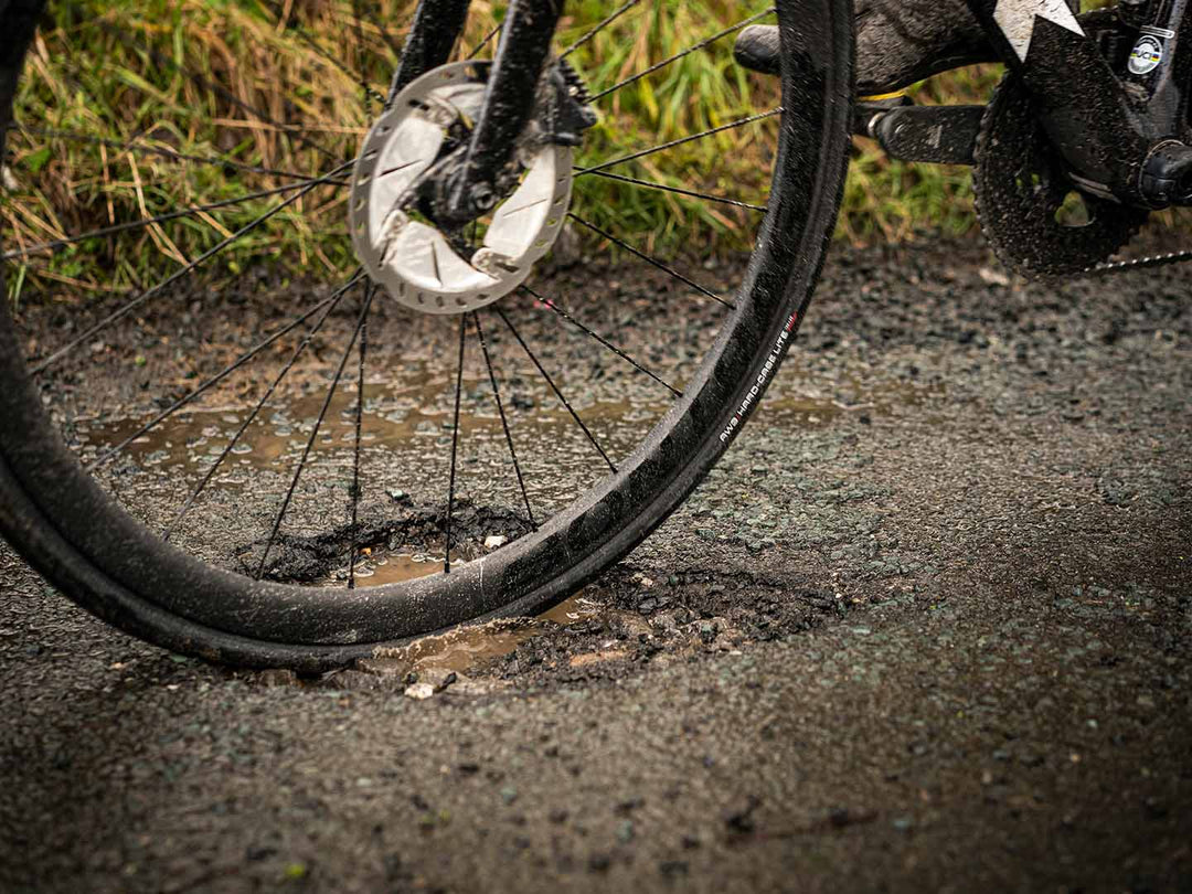 荒れた舗装路の水が溜まった穴を走行している様子