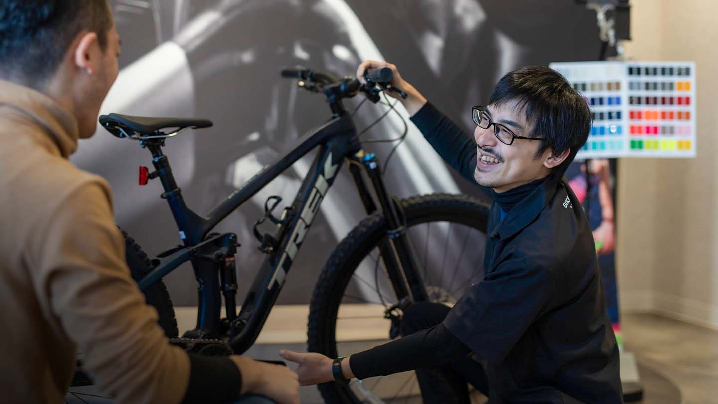 マウンテンバイクを笑顔で紹介するスタッフの写真
