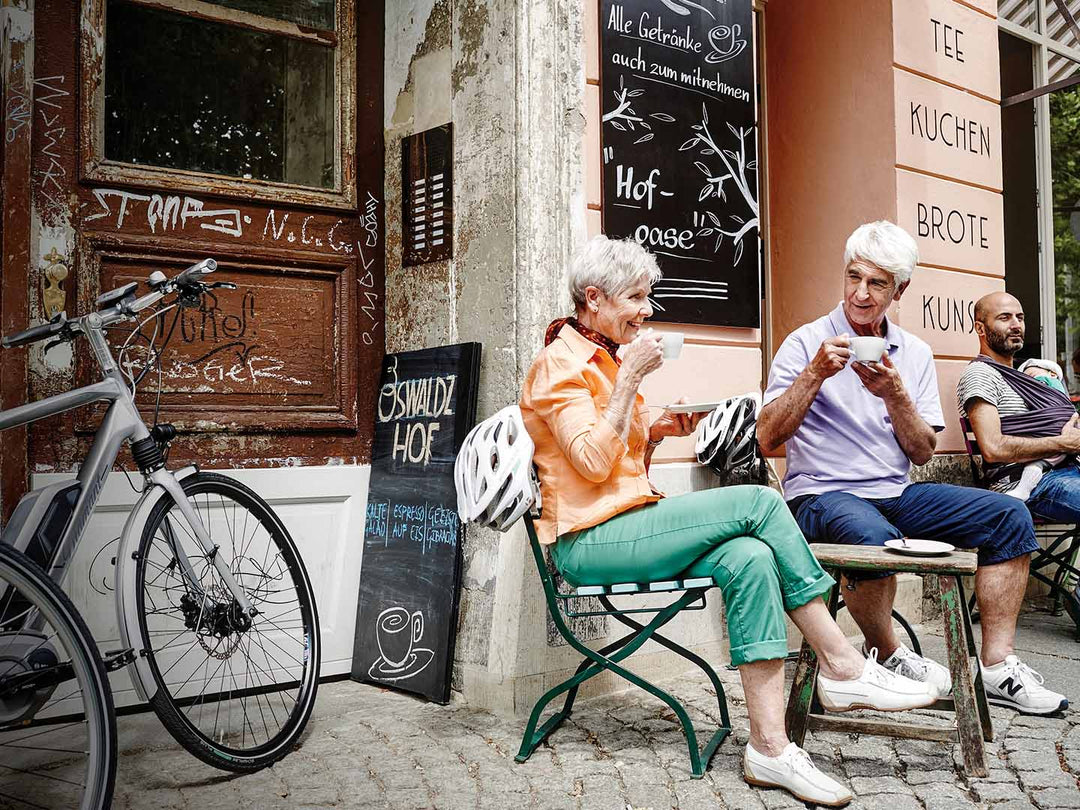 eバイクでのサイクリングの途中にカフェでコーヒーを飲む老夫婦の写真