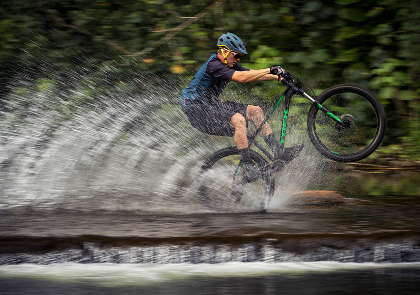 前輪を上げるマニュアルという動作をしながら浅い川をわたり水しぶきをあげている様子