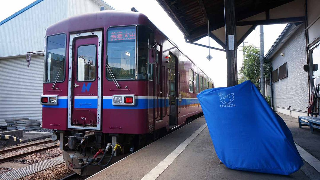 電車と輪行袋に入れたロードバイク。駅のホームにて。