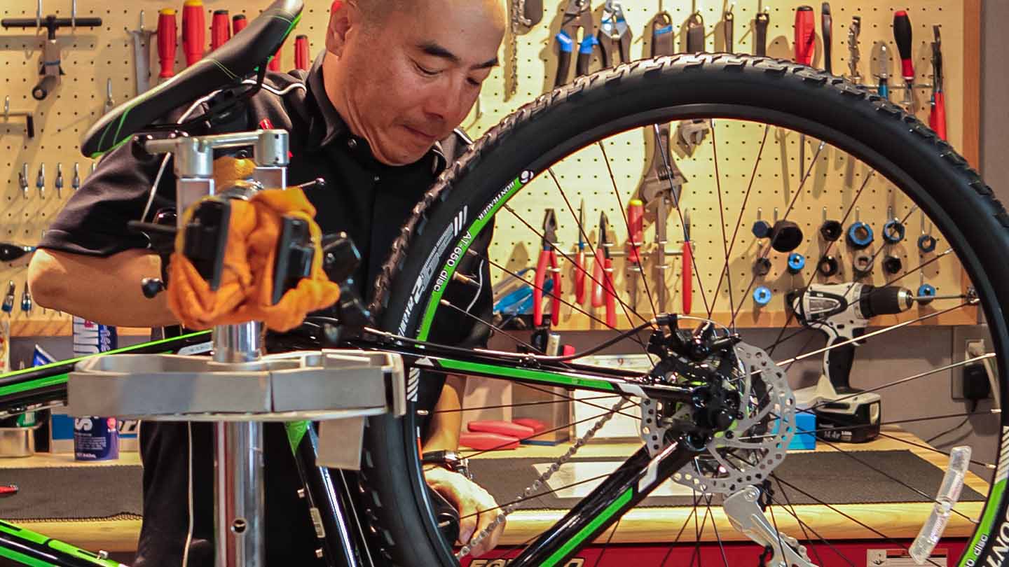 スポーツ自転車のメンテナンスをしているショップ店員の写真