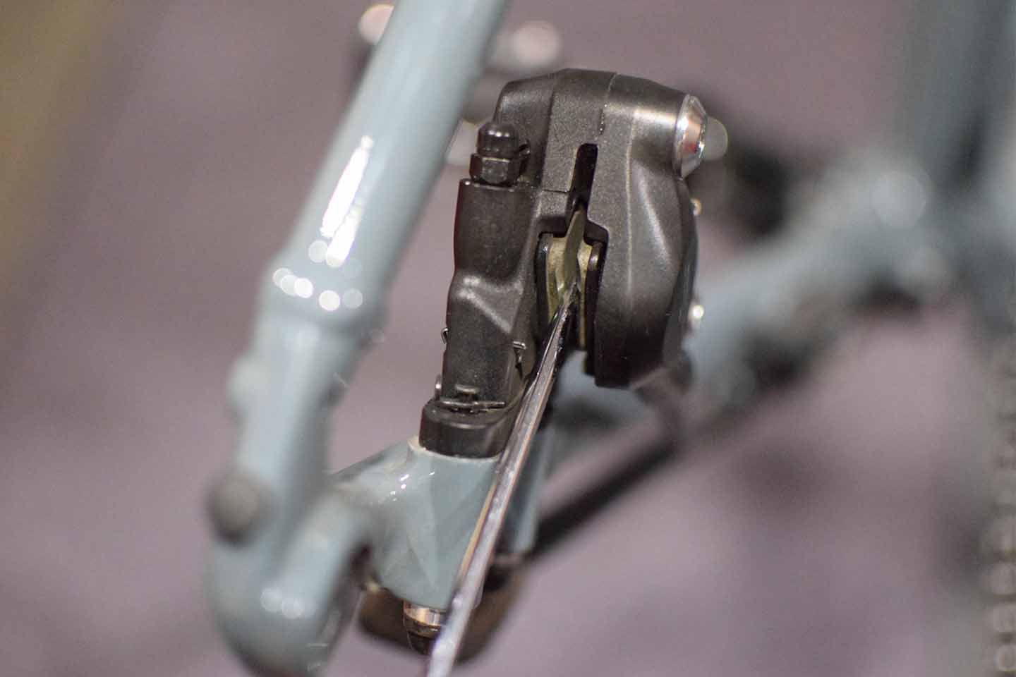 工具でパッドとピストンを戻している作業