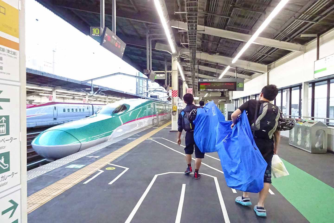 東北新幹線のホームを輪行袋を担いで歩くサイクリストの写真
