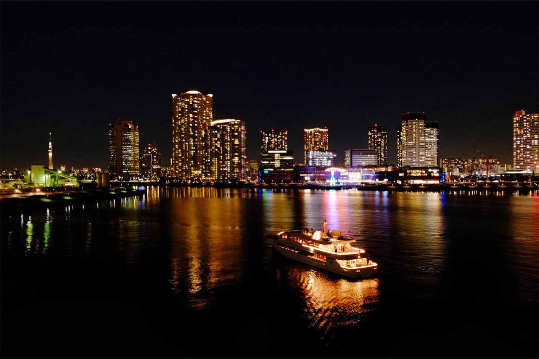 東京の隅田川を走る屋形船と高層ビルの夜景