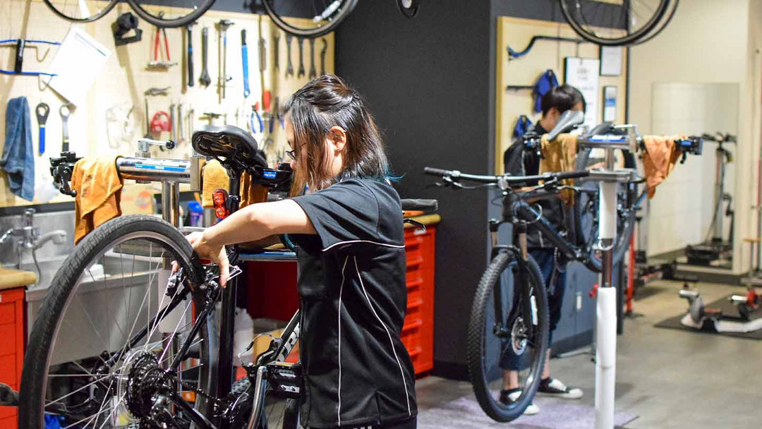 広いテックエリアで自転車のメンテナンスや組み立て作業を行うスタッフの様子