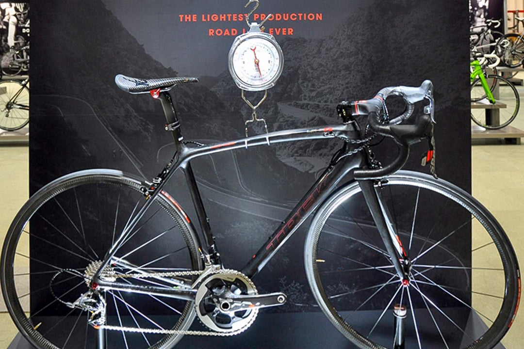 重さを測るバネばかりに超軽量ロードバイクを掛けて針が示す重量から軽さをアピールしている写真