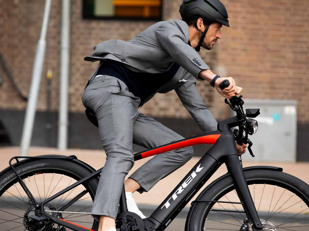 マットブラックにレッドの差し色がかっこいいeクロスバイクに乗るグレーのスーツを着た男性の写真