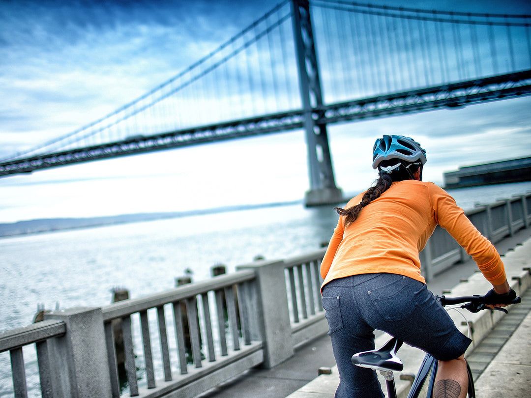 大きな橋の下を走るクロスバイクに乗った女性の写真