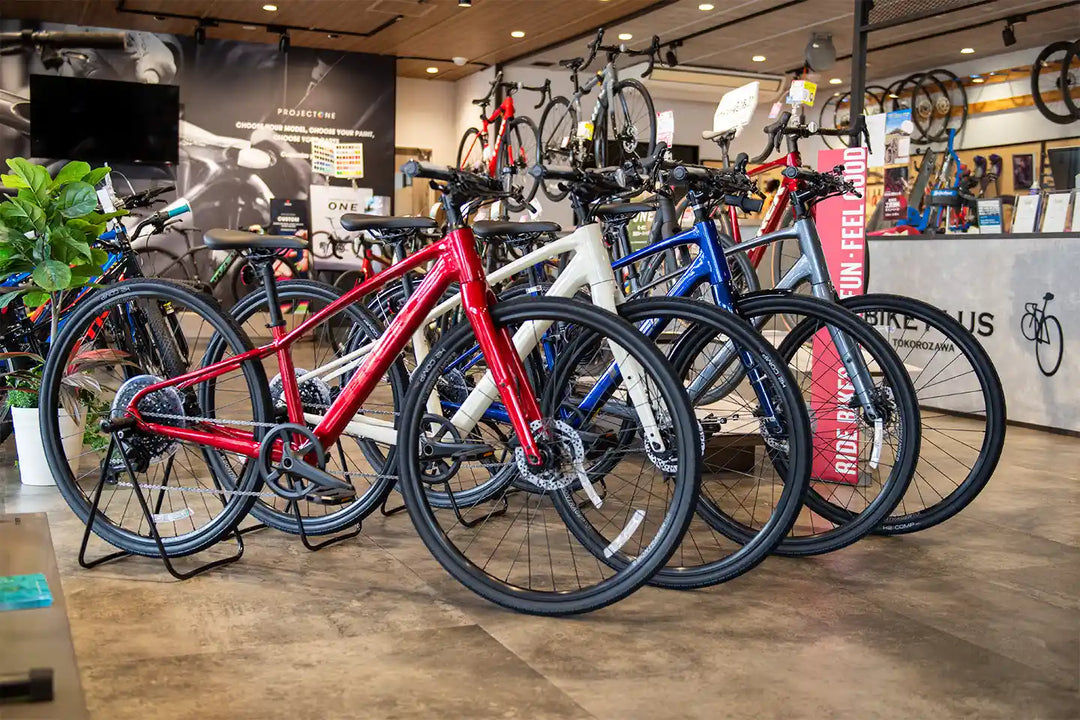 TREKのFX3のすべてのカラーを並べてバイクプラス所沢店の売り場で撮影。前から、クリムゾン、エラホワイト、ヘックスブルー、ギャラクティックグレーの順。